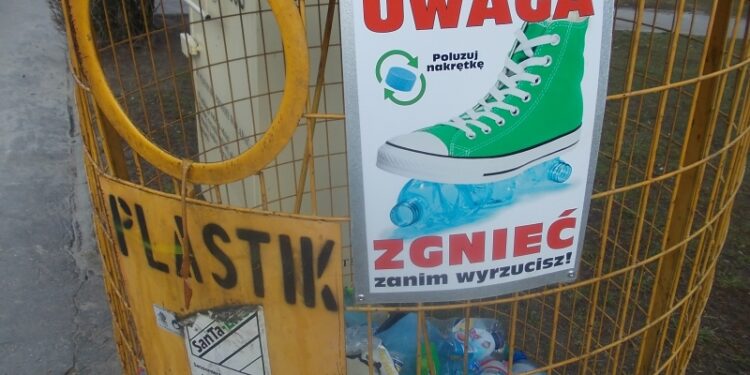 Tarnobrzeg. Pracownicy SanTa-EKO montują tabliczki edukacyjne, na pojemnikach przeznaczonych do selektywnej zbiórki odpadów.